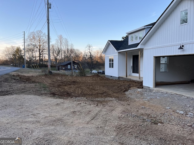 view of property exterior featuring dirt driveway and roof with shingles