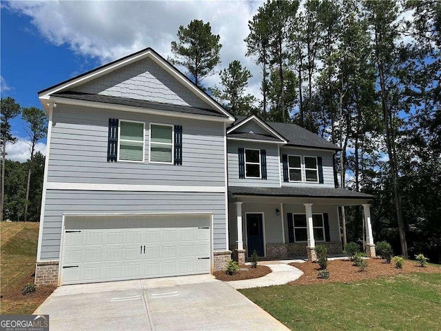 craftsman-style home with a garage, concrete driveway, stone siding, covered porch, and a front yard