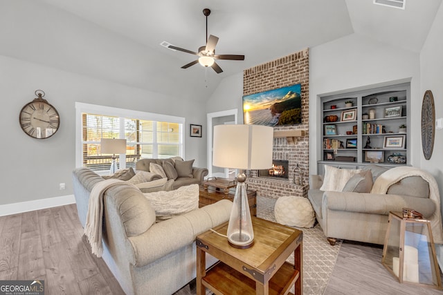 living room featuring lofted ceiling, visible vents, a fireplace, and light wood finished floors