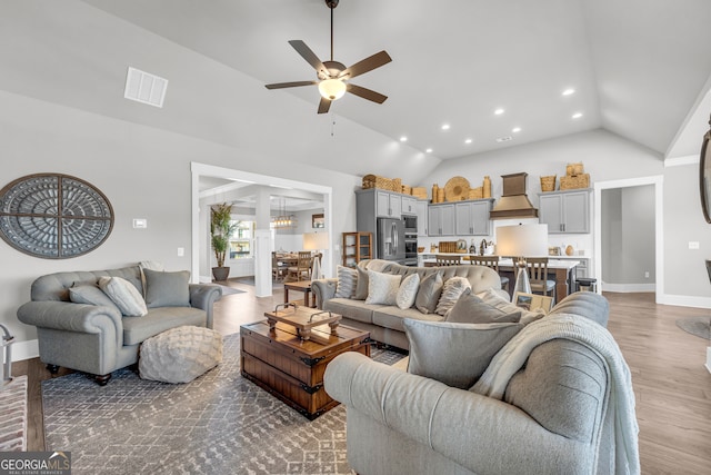 living room featuring lofted ceiling, wood finished floors, visible vents, a ceiling fan, and baseboards