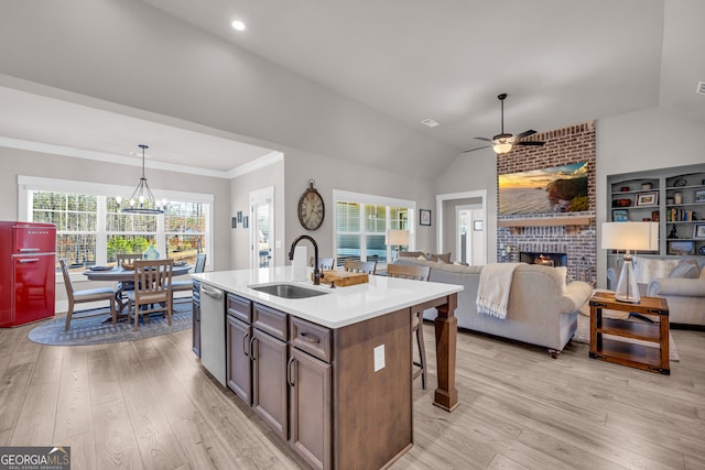 kitchen with pendant lighting, a center island with sink, light countertops, open floor plan, and a sink