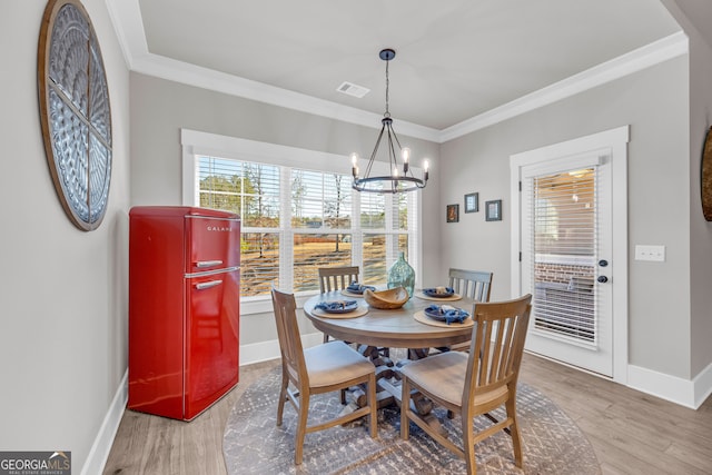 dining area with light wood-style flooring, visible vents, baseboards, and ornamental molding