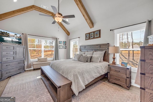 bedroom featuring high vaulted ceiling, light wood finished floors, multiple windows, and beam ceiling