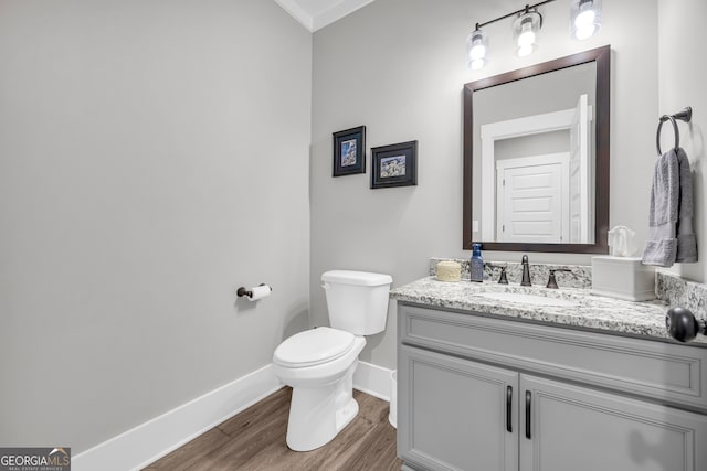 bathroom with baseboards, vanity, toilet, and wood finished floors