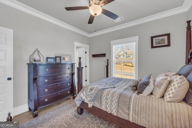 bedroom with visible vents, ornamental molding, ceiling fan, wood finished floors, and baseboards