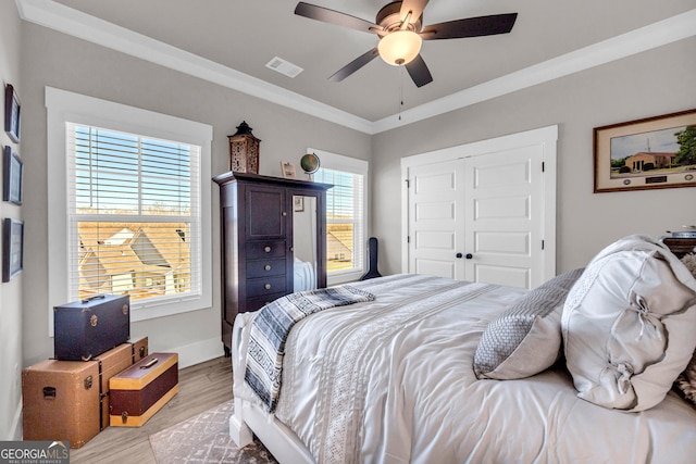 bedroom with ceiling fan, visible vents, a closet, light wood finished floors, and crown molding