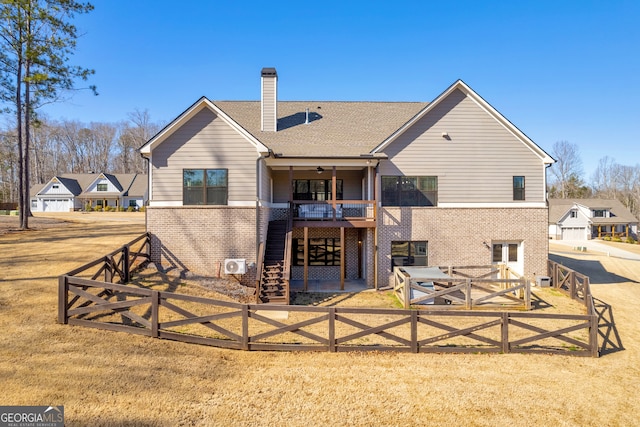 rear view of house with a chimney, stairway, fence private yard, a yard, and brick siding