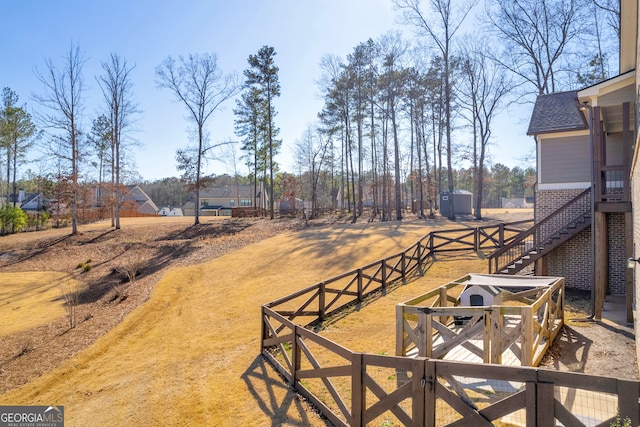 view of yard with a gate, fence, and stairway