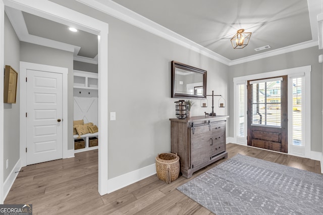 foyer entrance featuring baseboards, light wood finished floors, visible vents, and crown molding