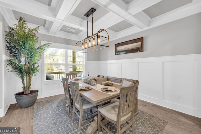 dining room with a decorative wall, coffered ceiling, wood finished floors, visible vents, and beam ceiling