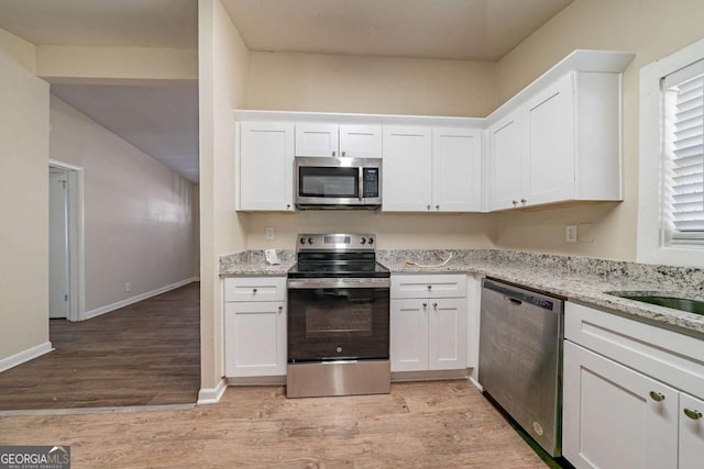 kitchen with appliances with stainless steel finishes, white cabinetry, and light stone counters