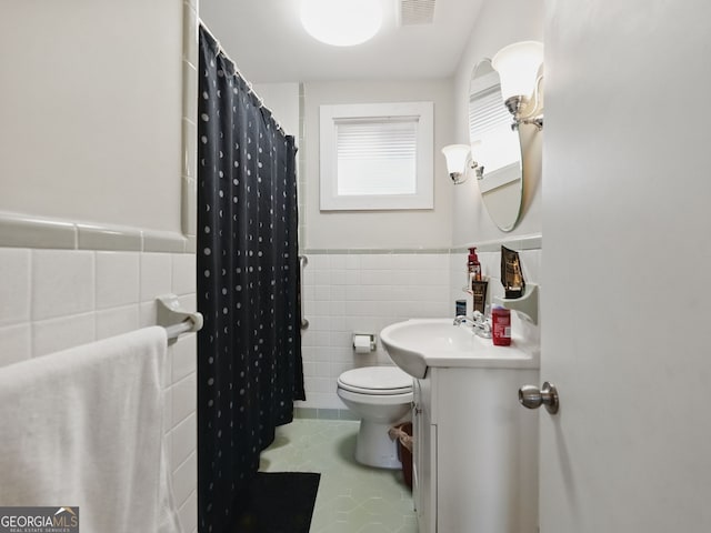 bathroom with tile walls, visible vents, wainscoting, vanity, and tile patterned flooring