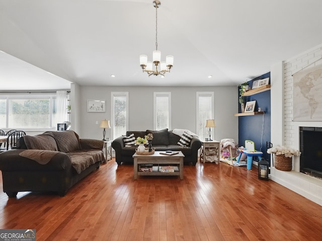 living area featuring a chandelier, a fireplace, wood finished floors, and recessed lighting