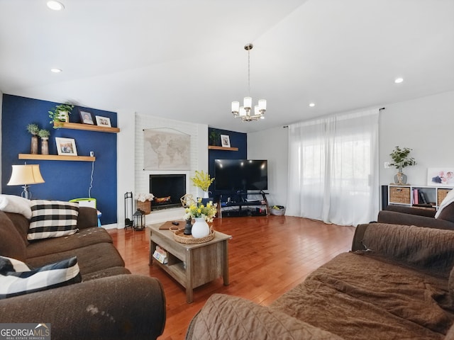 living room with a notable chandelier, recessed lighting, lofted ceiling, a brick fireplace, and wood finished floors