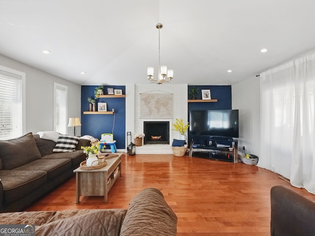 living room with a notable chandelier, a fireplace, recessed lighting, vaulted ceiling, and wood finished floors