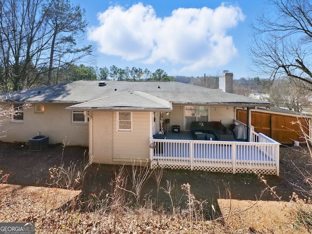 rear view of house featuring a deck, brick siding, a chimney, and central air condition unit