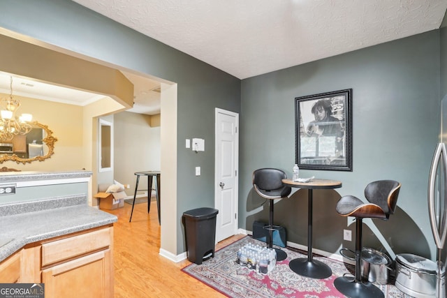 interior space featuring light wood-type flooring, a textured ceiling, baseboards, and an inviting chandelier