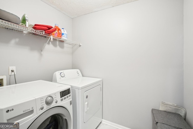 laundry area with laundry area, washer and clothes dryer, baseboards, and a textured ceiling