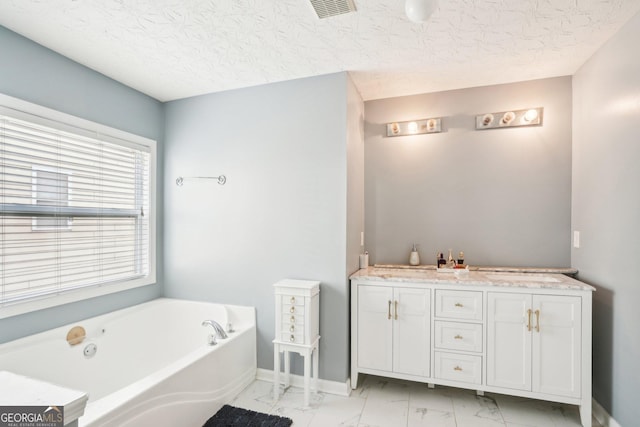 full bathroom featuring a bath, marble finish floor, a textured ceiling, and visible vents