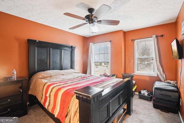 bedroom with a textured ceiling, baseboards, a ceiling fan, and light colored carpet