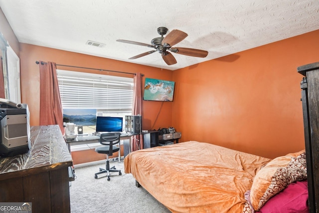 carpeted bedroom featuring a textured ceiling, ceiling fan, and visible vents