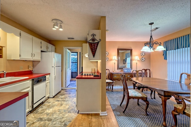 kitchen featuring a chandelier, a sink, white cabinetry, dishwasher, and decorative light fixtures