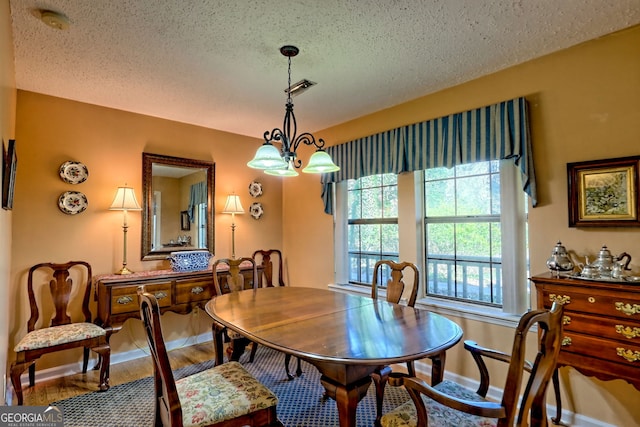 dining room with a textured ceiling, a notable chandelier, wood finished floors, visible vents, and baseboards