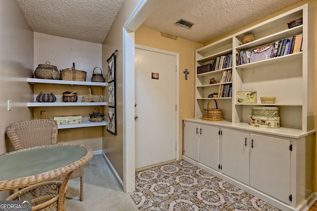 interior space with visible vents, a textured ceiling, and baseboards