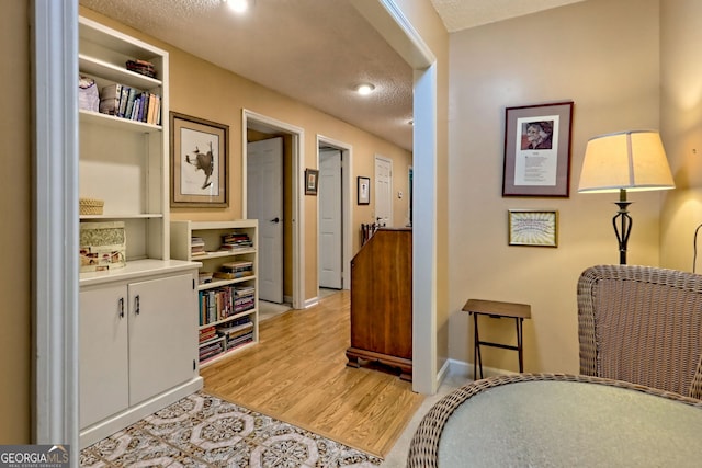 interior space with a textured ceiling, light wood-style flooring, and baseboards