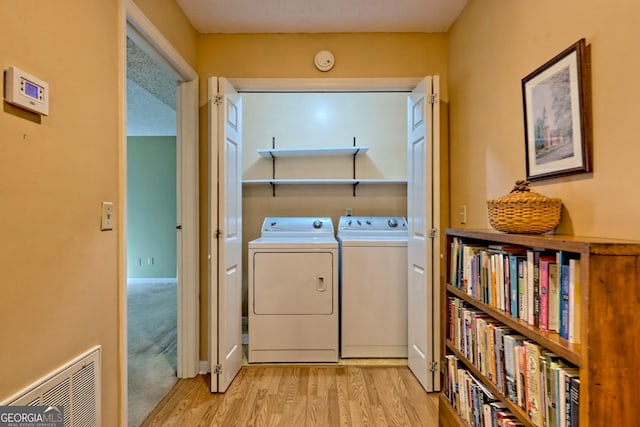 laundry area featuring light wood-type flooring, laundry area, visible vents, and washing machine and clothes dryer