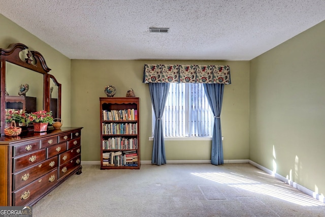 living area with a textured ceiling, baseboards, visible vents, and light colored carpet