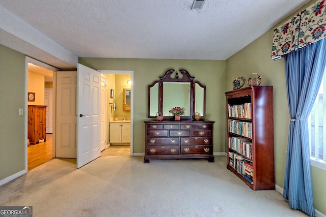 bedroom featuring light carpet, connected bathroom, baseboards, and a textured ceiling