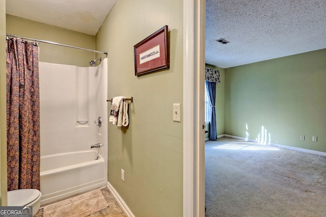 bathroom featuring a textured ceiling, shower / bath combination with curtain, visible vents, and baseboards