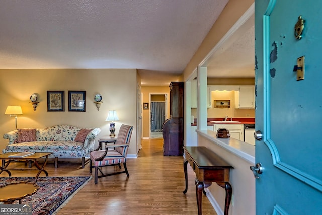 living room with a textured ceiling, baseboards, and wood finished floors