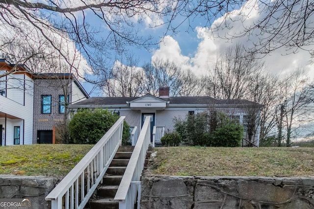 view of front of house with a chimney, stairway, a front lawn, and brick siding