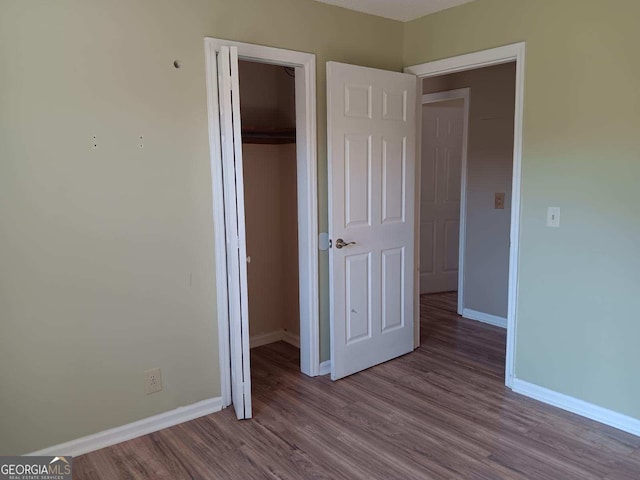 unfurnished bedroom featuring light wood-style flooring, baseboards, and a closet