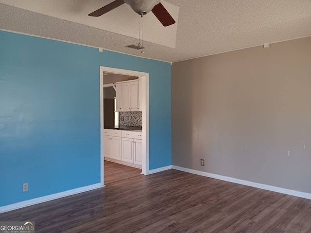 unfurnished room featuring baseboards, dark wood-type flooring, visible vents, and a ceiling fan