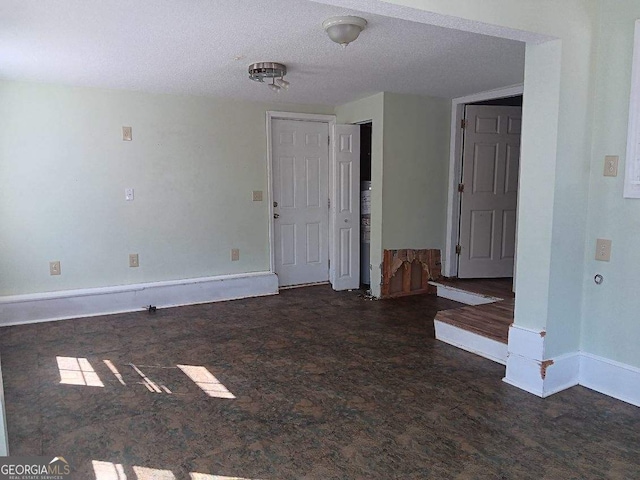 empty room with a textured ceiling and baseboards