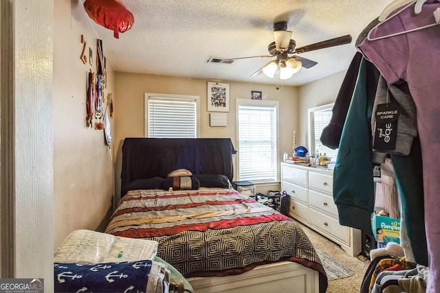 bedroom featuring a ceiling fan, visible vents, carpet flooring, and a textured ceiling