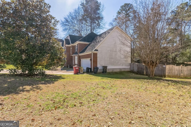 view of home's exterior with a yard, brick siding, fence, and an attached garage