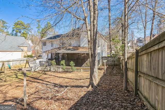 rear view of house with a fenced backyard and a sunroom