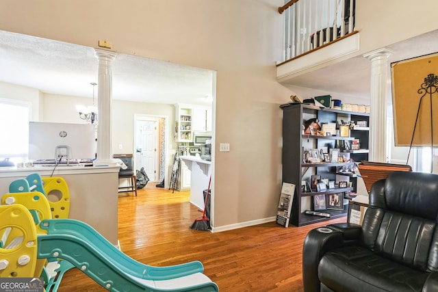 living area with decorative columns, baseboards, and wood finished floors