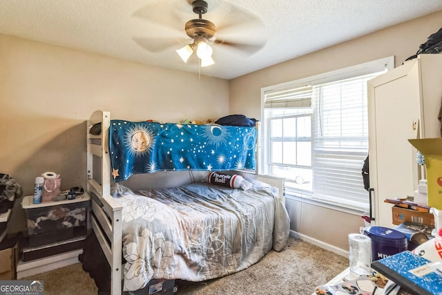 carpeted bedroom featuring a textured ceiling, ceiling fan, and baseboards