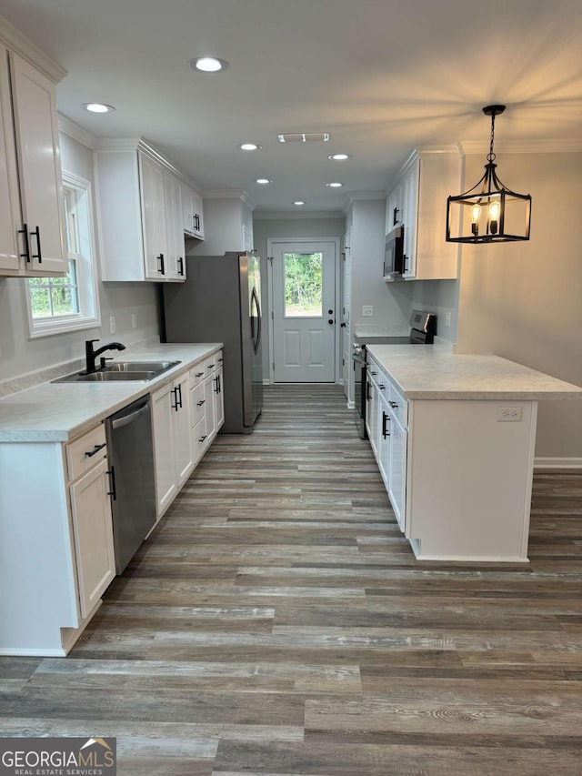 kitchen with a sink, white cabinets, light countertops, appliances with stainless steel finishes, and decorative light fixtures