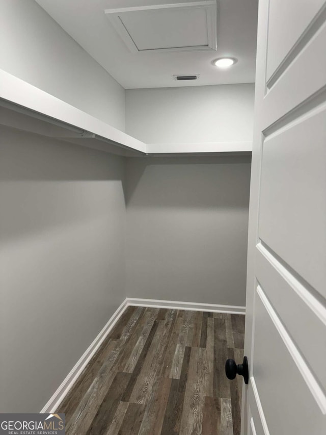 spacious closet featuring attic access, visible vents, and dark wood finished floors