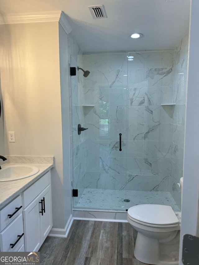 bathroom featuring a marble finish shower, visible vents, toilet, vanity, and wood finished floors