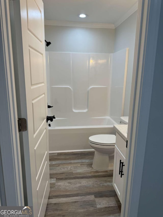 bathroom with toilet, wood finished floors, crown molding, vanity, and shower / bathing tub combination