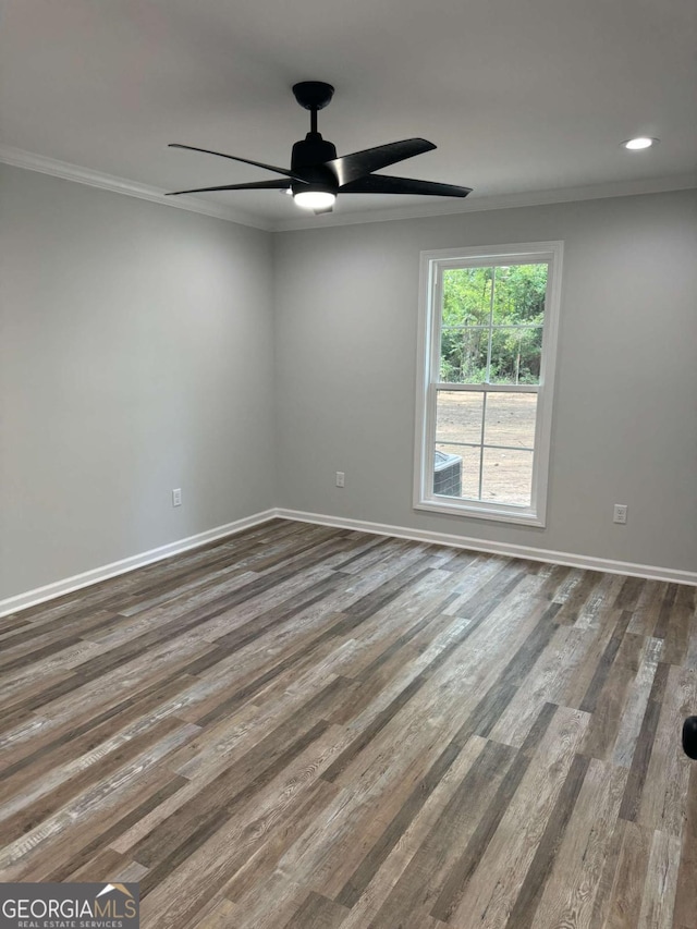 empty room featuring ornamental molding, dark wood-style flooring, and baseboards