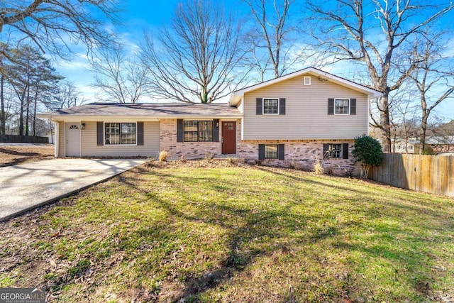 tri-level home with a front yard, concrete driveway, and fence