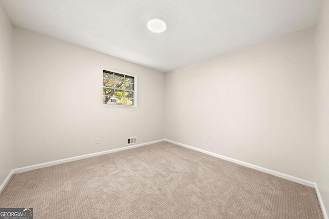 spare room with carpet floors, visible vents, and baseboards